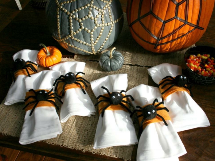 decoración halloween, servilletas decoradas con arañas, dos calabazas en naranja y verde con ornamentos
