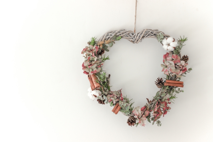 decoracion navideña manualidades, corona de navidad en forma de corazon, ramas secas, canela y piñas naturales, flores rosadas