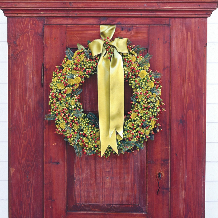 adornos de navidad caseros, corona de navidad en verde y amarillo, bayas y cinta dorada, armario de madera