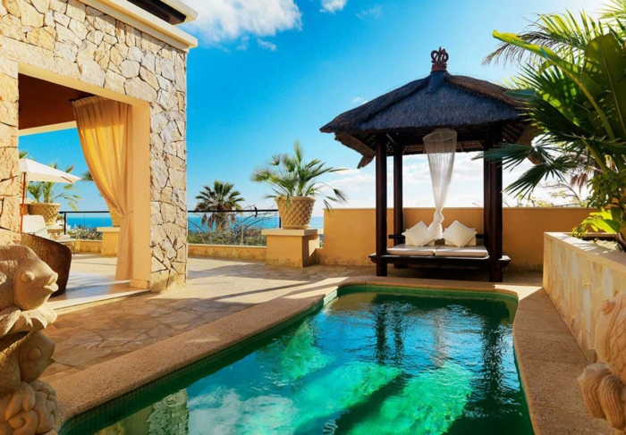 piscinas de obra, casa de piedra en la costa, quiosco con cojines, piscina pequeña decorativa, cielo azul, palmeras