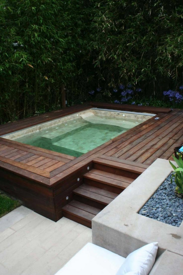 piscinas prefabricadas, piscina pequeña rectangular integrada en tarima, planta sobre piedritas, sofá con cojín