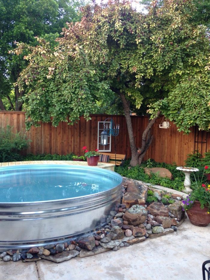 piscinas pequeñas, patio con piscina de metal redonda, decoración con piedras, valla de madera, árbol grande