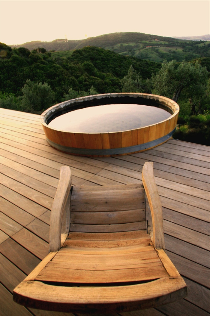 piscinas prefabricadas, piscina redonda de madera, suelo de tarima, silla de madera, paisaje con montaña verde