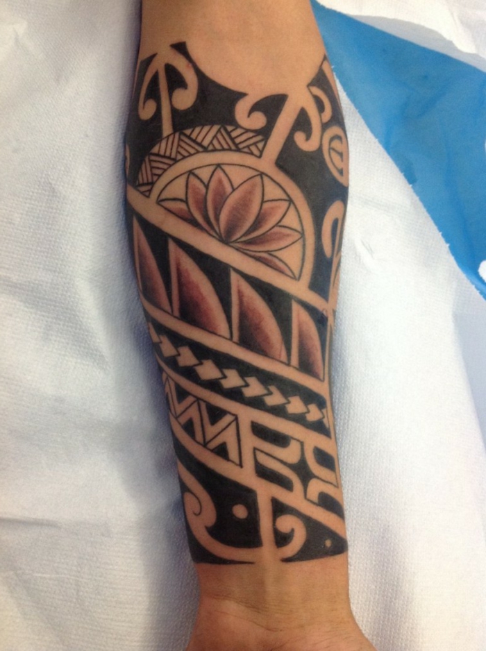 tatuaje maori, tatuaje en rojo y negro en antebrazo de hombre, motivos polinesios,punta de lanza