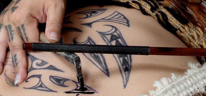 brazalete maori, técnica antigua maori para hacer tatuajes con palo y pluma, manos de mujer, espalda tatuada