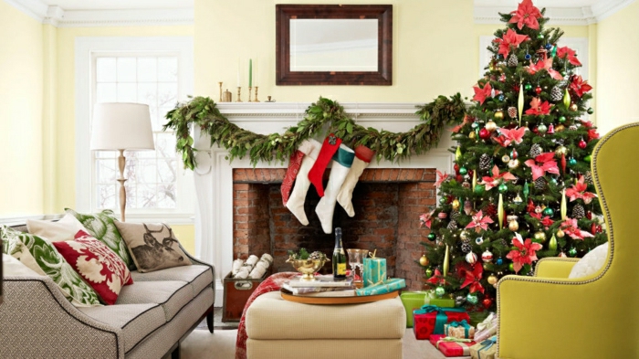 arbol de navidad original, decorado con grandes flores navideños rojos y juguetes de diferente forma, cojones con motivos navideños, guirnalda verde en la chimenea