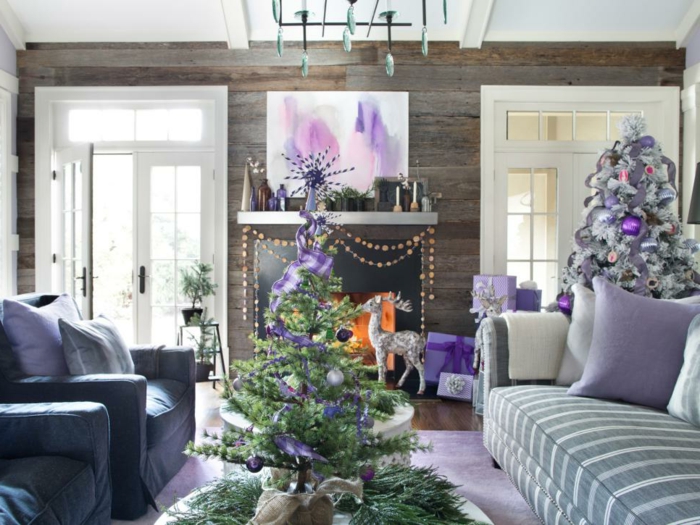 arbol de navidad original, salón decorado en color lila y blanco, grandes sofás y chimenea acogedor, dos árboles de navidad