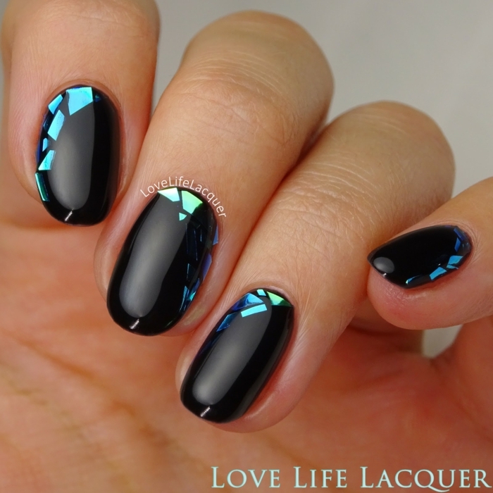 uñas pintadas, ejemplo de uñas de media longitud pintadas en negro con brillo y decoradas de partículas brillantes en tonos azules