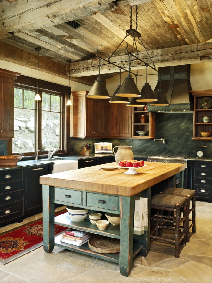 cocina americana, pequeña cocina acogedora en estilo rústico con techo de madera y lámparas de hierro vintage, mesa de madera con patas en verde, armarios en azul oscuro