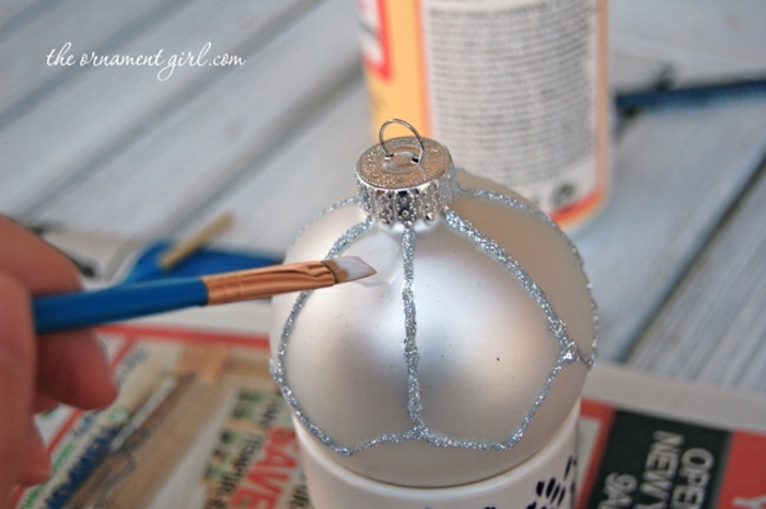 como hacer bolas de navidad, pasos fáciles para decorar un adorno navideño, poner pegamento blanco sobre la bola