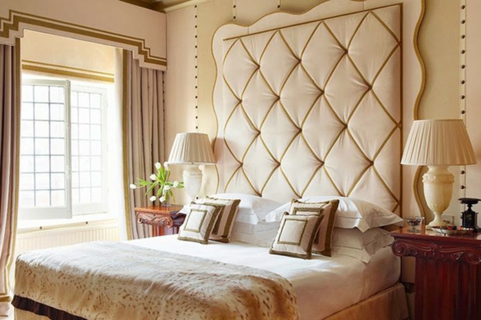 cabeceros de cama, habitación en beige con cabezal original capitoné y cama doble con cojines de estilo, grandes ventanas con cortinas en beige