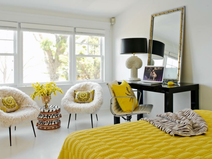 colores cálidos, habitación grande y luminosa en blanco con mucha decoración en amarillo, cojines y cobijas en color mostaza, grande espejo vintage