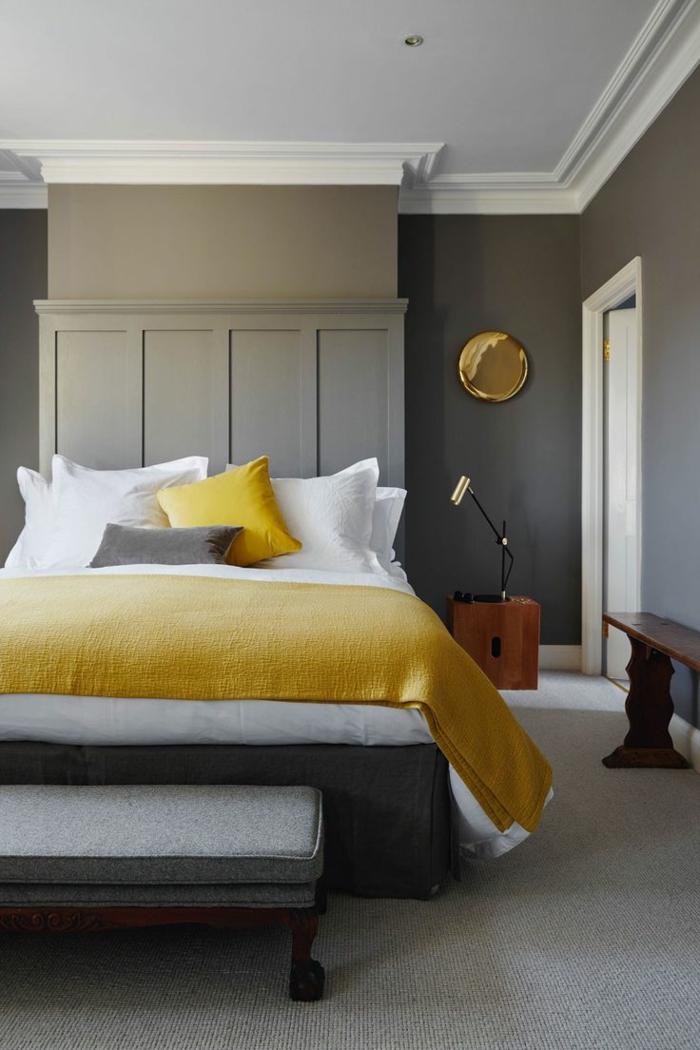 habitaciones de matrimonio, dormitorio en gris, blanco y amarillo, paredes en gris, cama matrimonio con pie de cama, suelo con moqueta y banco de madera