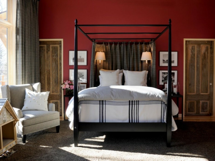 dormitorios de matrimonio, paredes en rojo intenso que está muy de moda, cama de madera en negro con grande marco, dos puertas de madera