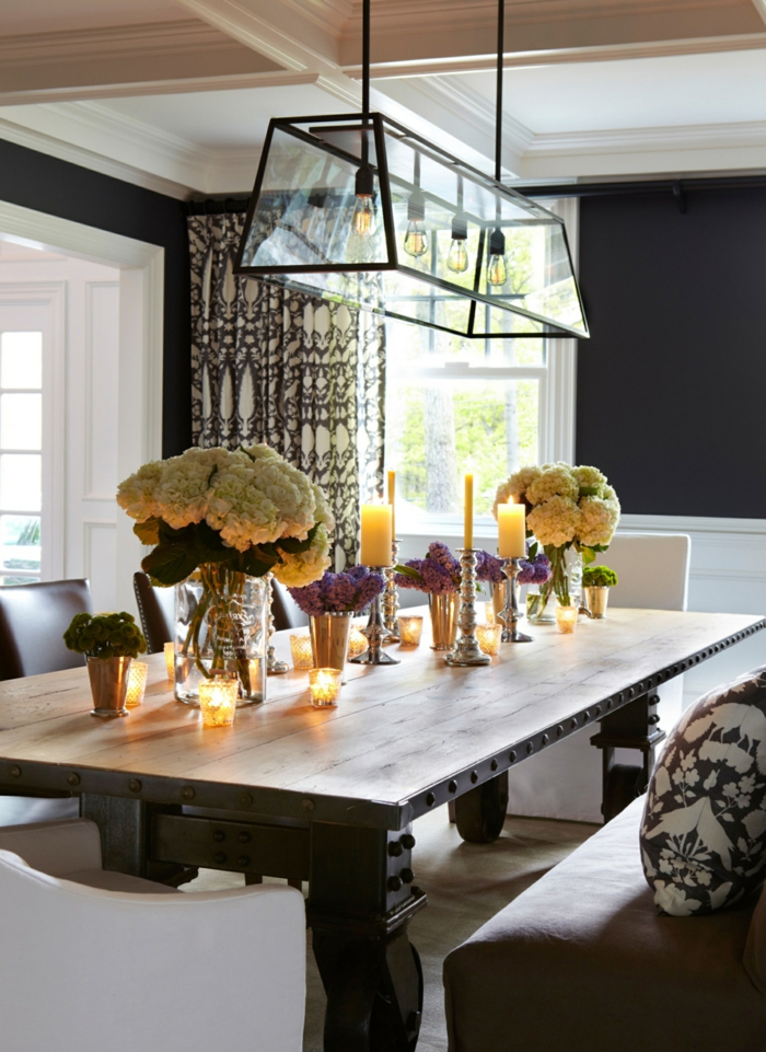 muebles de comedor, comedor con toque rústico, grande mesa de madera y mucha decoración de flores y velas, paredes en negro 