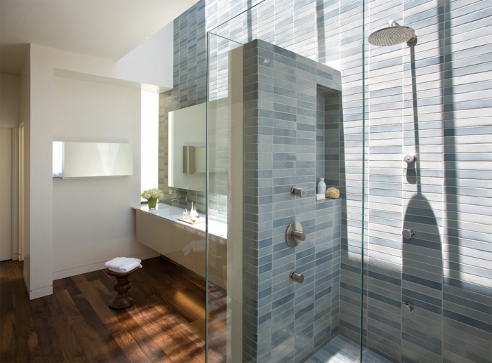 platos de ducha de obra, baño con paredes de baldosas azules, mucha luz natural, ducha de obra con efecto lluvia y nicho en la pared, suelo laminado