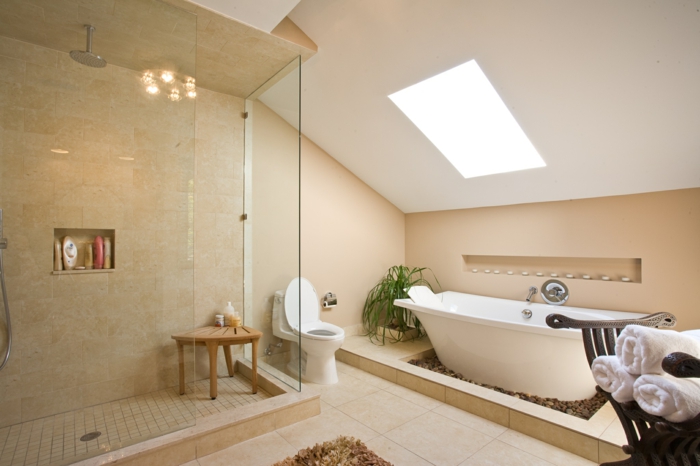 duchas modernas, baño grande con techo inclinado y ventana, bañera blanca, suelo de baldosas, ducha de obra delimitado con mampara, silla de madera