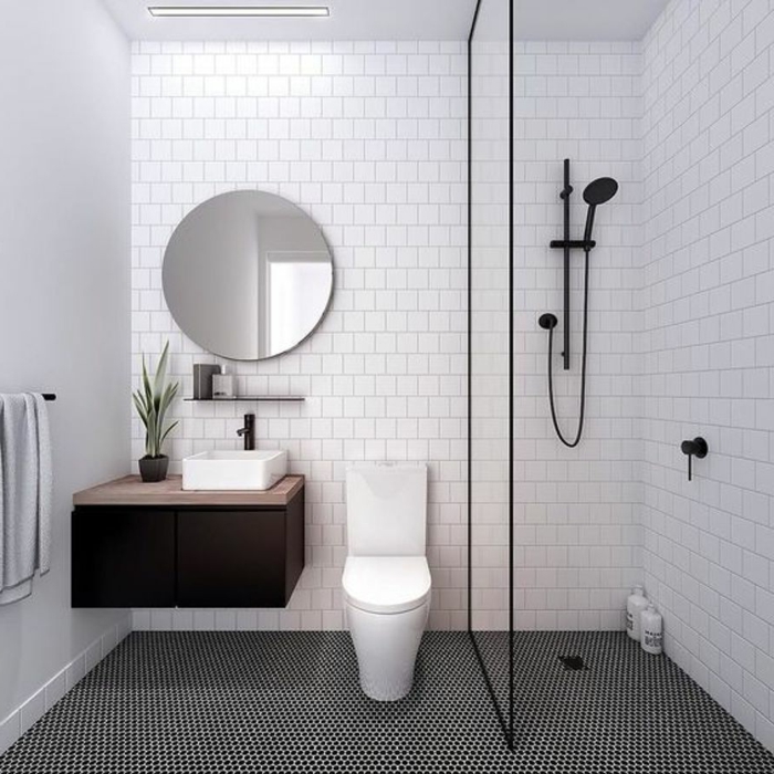 duchas modernas, baño pequeño en blanco y negro, lavabo pequeño, ducha negra de mano, mampara de vidrio, paredes con baldosas