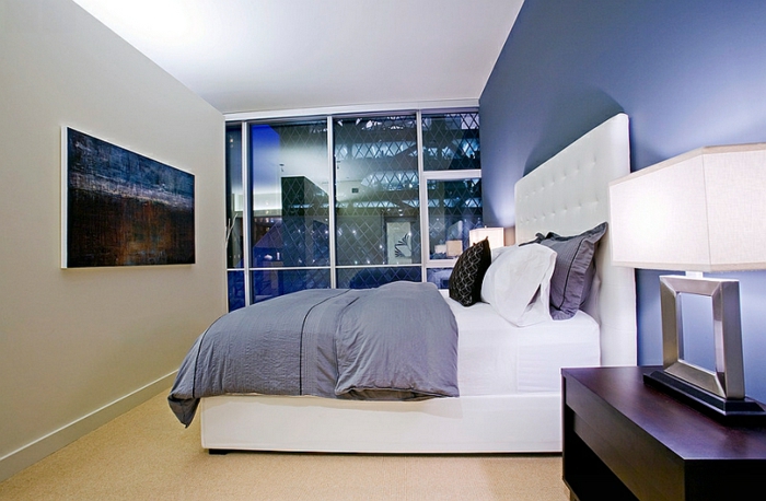 tonos de azul, habitación moderna en azul atenuado, muebles de madera y cama grande con cabecero en capitoné, ventanales con vista