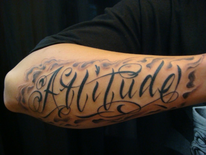 tipos de letras para tatuajes, antebrazo hombre, tatuaje con palabra, letras grandes en cursiva con adornos