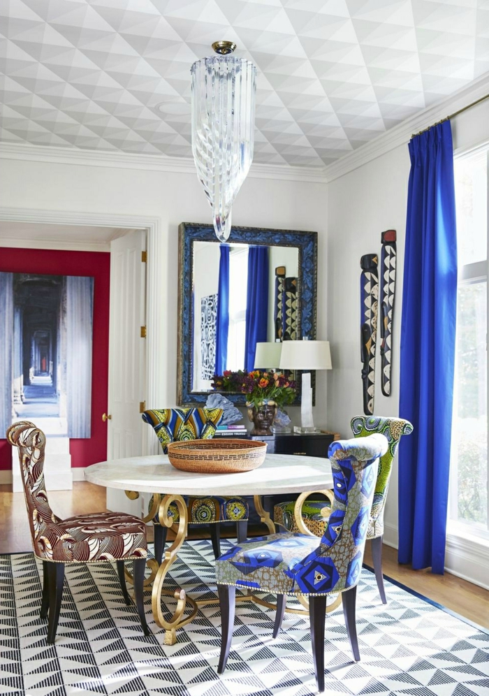 salon comedor, propuesta muy elegante de sillas tapizadas en diferentes colores, cortinas en azul intenso y lámpara muy original en el techo 