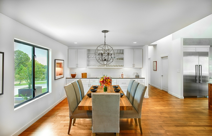 comedor moderno, piso espacioso con pequeña cocina en blanco y grande comedor sin puertas, mesa de madera y sillas en gris
