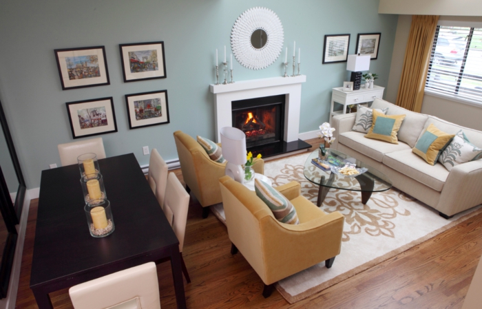 muebles de salon modernos, salon acogedor con rincón para comer mesa de madera decorada con velas y sillas en beige, paredes en azul claro, sofás en beige
