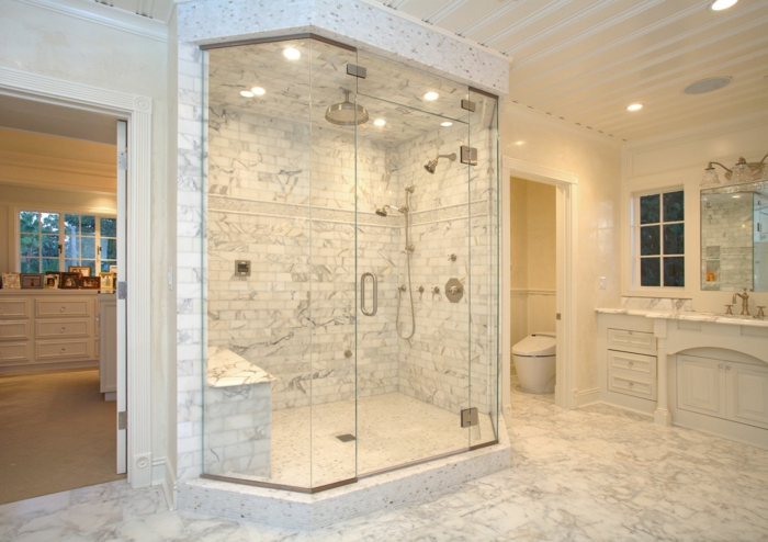 duchas de obra, baño de mármol con ducha de obra delimitada con paredes y vidrio, ducha efecto lluvia, suelo con láminas de madera 