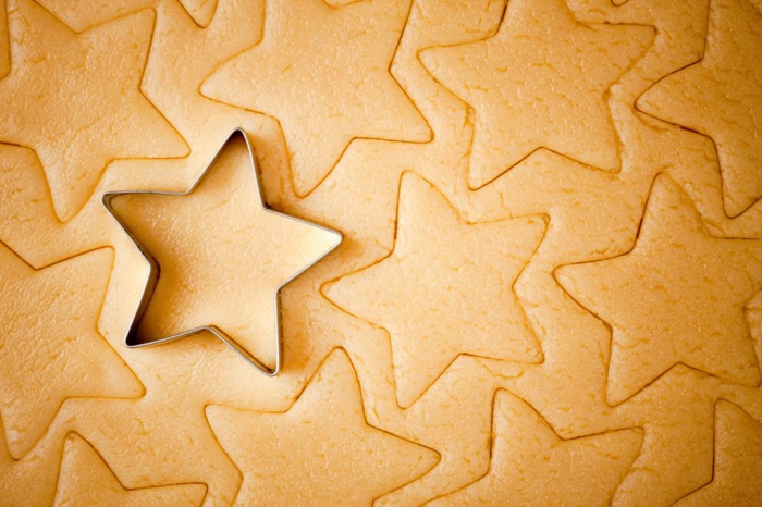 receta de galletas de mantequilla, galletas de navidad con la forma de estrella, cortar las piezas con cortador de galletas