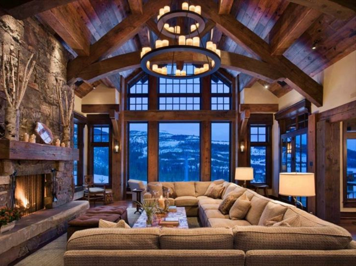 casa de madera, precioso salón con candelabro vintage, grande sofá en beige y paredes de piedra, vista a la montaña