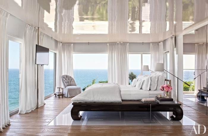 habitaciones modernas, habitación espaciosa con grandes ventanales y cortinas en blanco, cama de madera con patas vintage, vista al mar