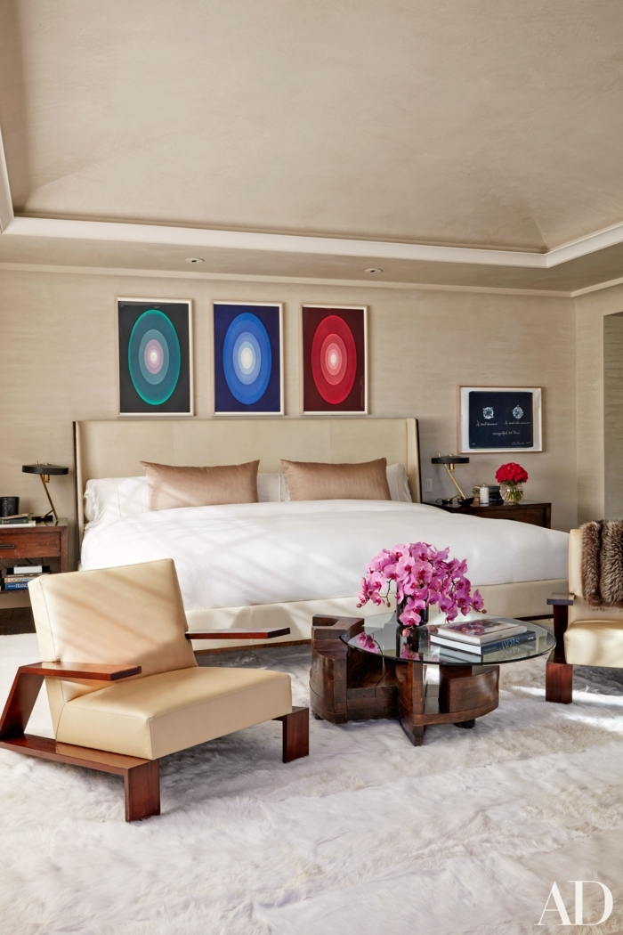 dormitorios de matrimonio, elegante habitación en beige con decoración en la pared, alfombra peluda en blanco y sillones modernos tapizados de piel 
