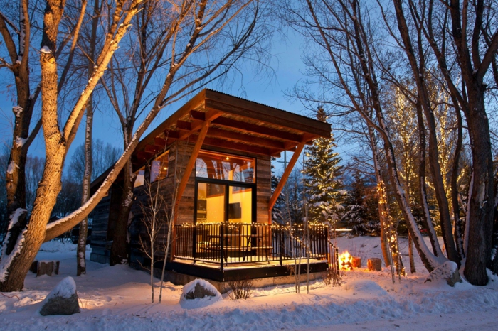 casa de madera, casa de diseño moderno con pequeña veranda decorada de bombillas, árboles con decoración de navidad