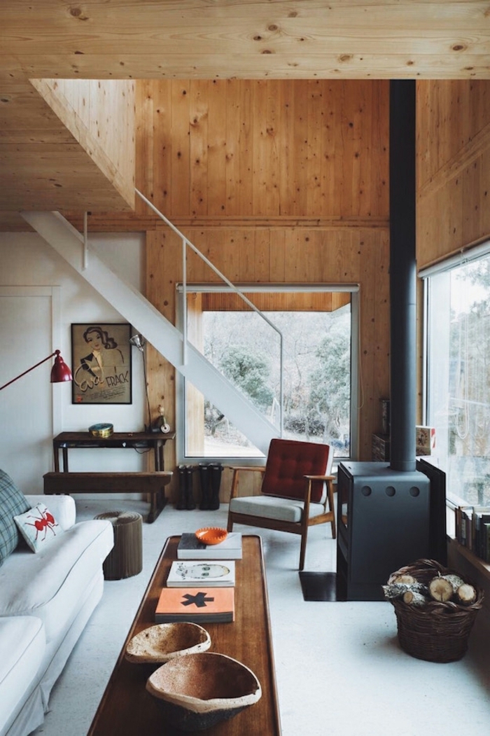 cabañas de madera, salón de maravilla en una casa de campo, paredes y techo con vigas de madera, mesa larga de madera y sofá tapizada en blanco 