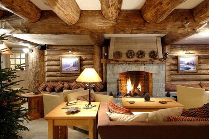 cabañas rurales, interior de encanto decorado en estilo rústico, grande chimenea de piedra, mesas de madera, techo con grandes vigas de madera