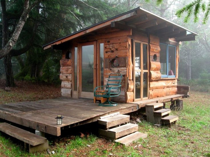 casitas de madera, cabaña de madera con veranda, pequeña casa de madera con ventanales colocada en el bosque