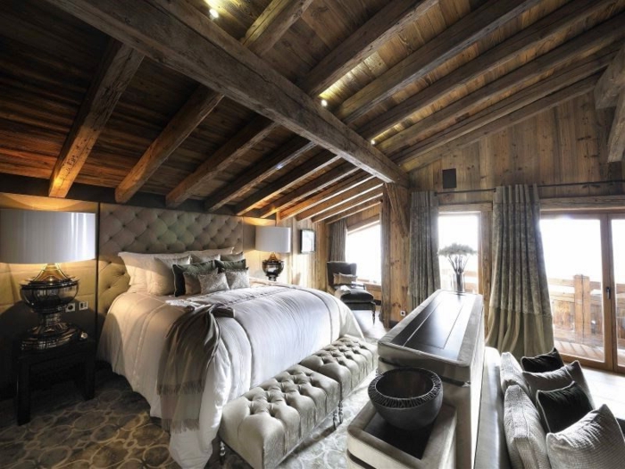 casitas de madera, grande dormitorio con vista, techo inclinado con vigas de madera, cabecero de cama y pie de cama en capitoné