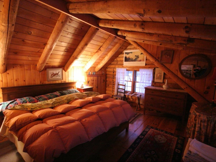cabañas con encanto, habitación acogedora colocada en la buhardilla, techo inclinado con vigas de madera, cama doble hecha de madera