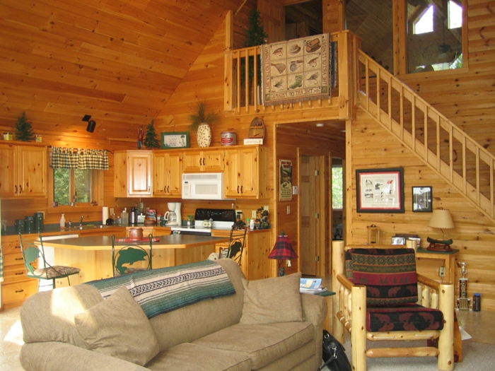 cabaña de madera, interior con vigas de madera, cabaña en dos plantas con techo inclinado, sofá cómoda en beige