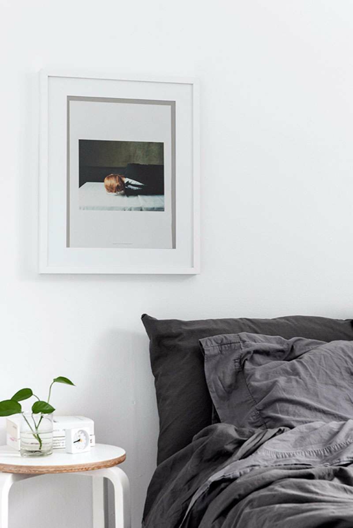 ideas para decorar una habitacion, habitación en estilo minimalista, sábanas en gris, mesa de madera pequeña. pintura moderna en la pared