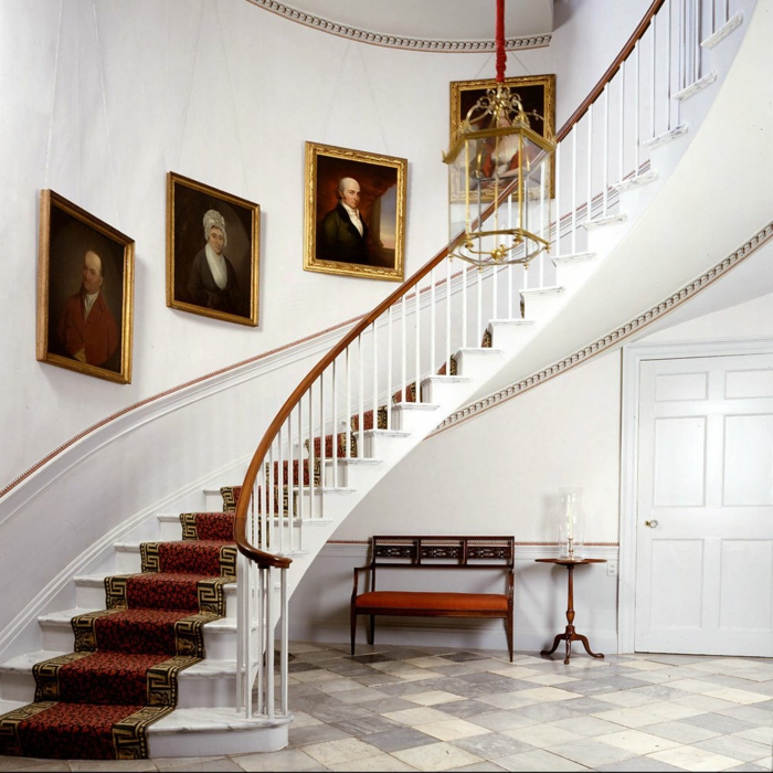 barandillas escaleras, recibidor de lujo, escalera de obra grande con alfombra, lampara colgande, retratos al oleo con marcos dorados