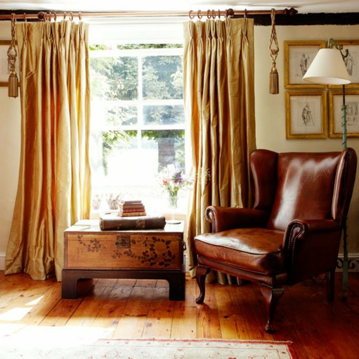 decoración vintage, salón decorado en estilo clásico con grande sillón de piel y caja de madera, cortinas de satén en color ocre