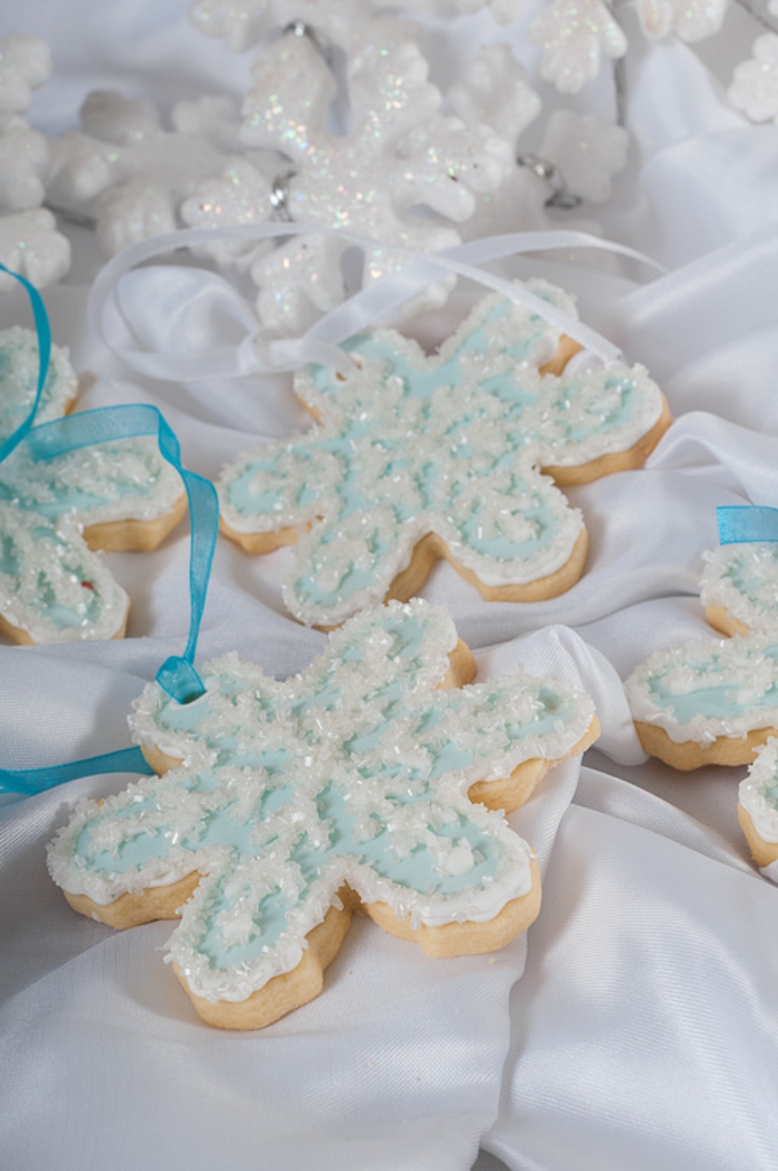 receta galletas mantequilla, bonitos copos de nieve en blanco y azul, galletas con glaseado y cintas azules