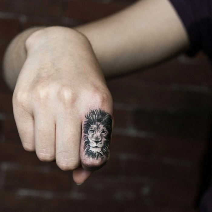 tatuaje corazon, dedo índice con tatuaje cabeza de león detallado en la falanga, propuesta para hombres y mujeres