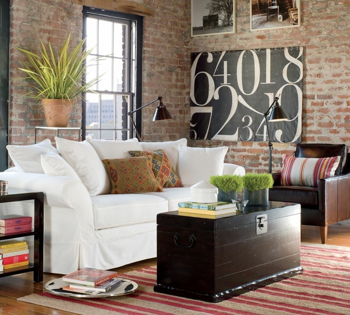 revestimiento paredes, salón pequeño con ventana grande, sofá blanco y mesa hecha con caja de madera, parede de ladrillo visto con cuadros