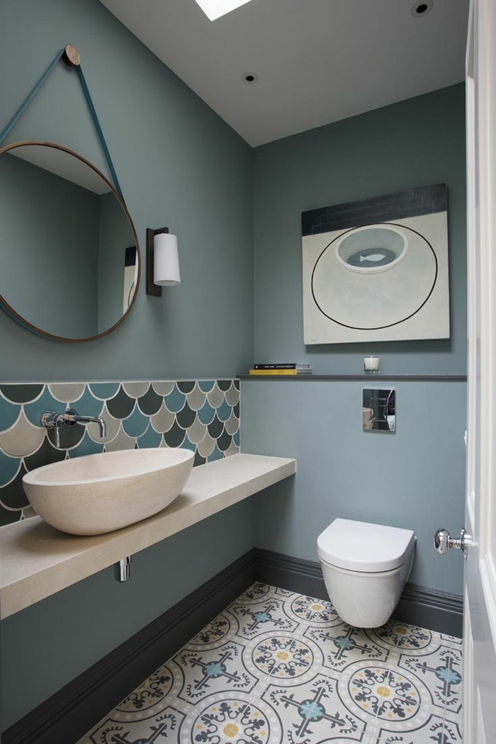cuadros decorativos, baño moderno en blanco y azul, espejo redondo, pintura abstracta con una pez, suelo con azulejos