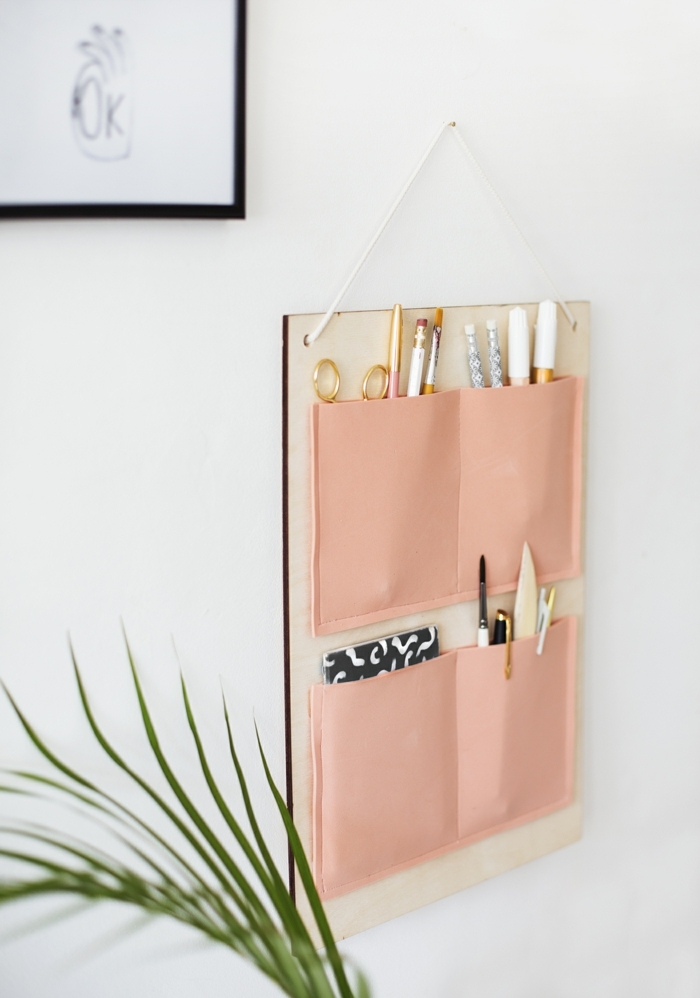 manualidades sencillas, decoración original para las paredes, tablero de madera con bolsillos de tela en color rosado 