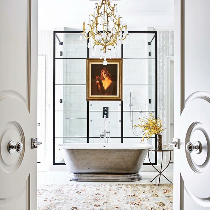 marcos vintage, baño de lujo con alfombra y bañera, lámpara de araña, retrato de mujer en marco dorado, ducha con mampara de vidrio