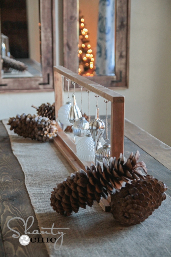 centros de navidad, ornamentos de cristal para el árbol de navidad colgados en un marco de madera, piñas decorativas