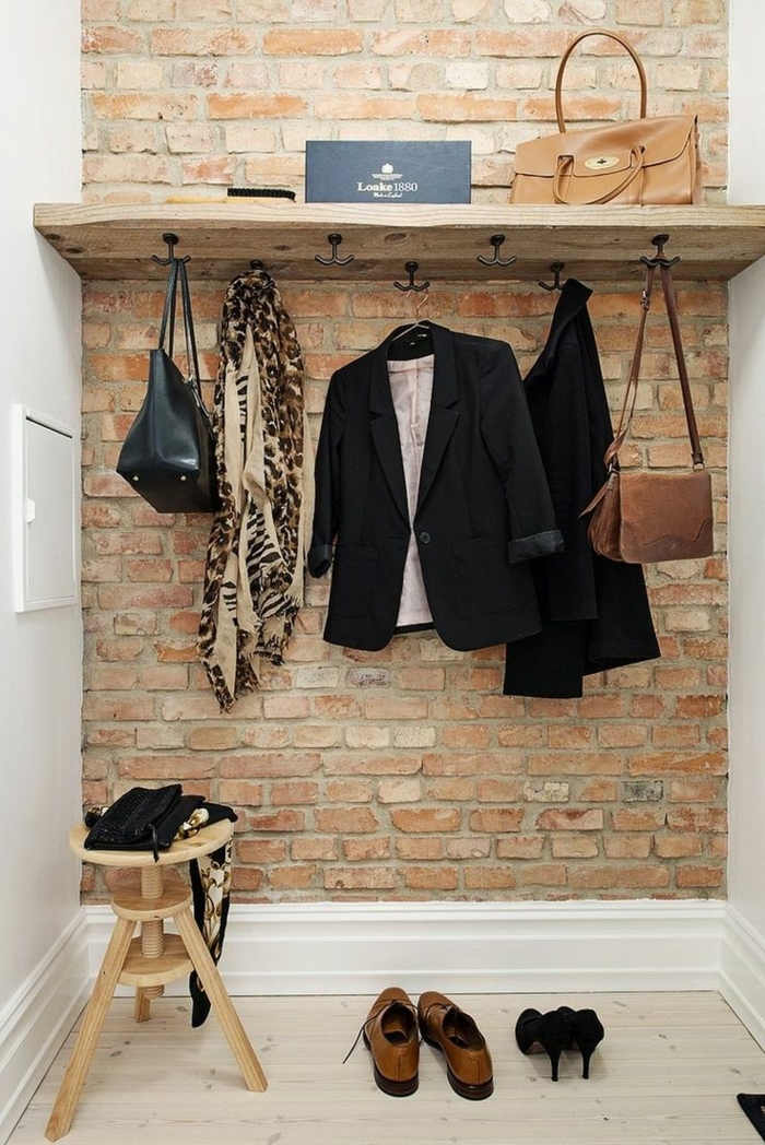 recibidores pequeños, recibidor con pared de ladrillo visto, percha con ropa y bolsas, silla pequeña de madera, decoración moderna